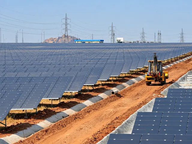 Solar-panel arrays and a yellow construction vehicle at Pavagada Solar Park